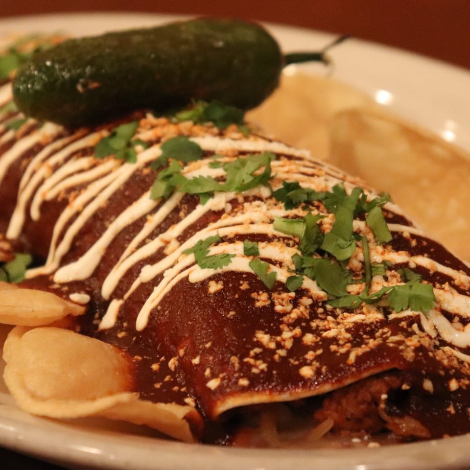 El Rey Azteca's Mexican burrito, topped with rich mole sauce, crema, cilantro, and a jalapeño.