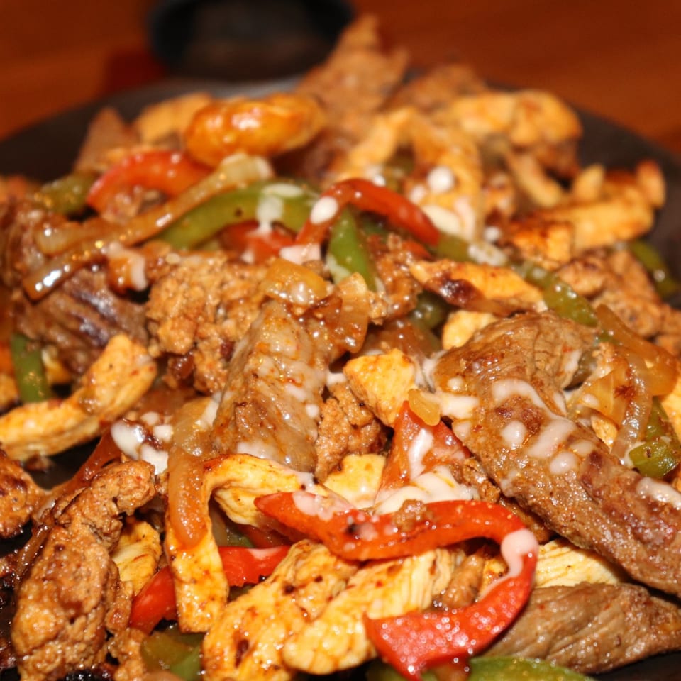 El Rey Azteca's sizzling fajitas with chicken, steak, peppers, and onions, topped with melted cheese.